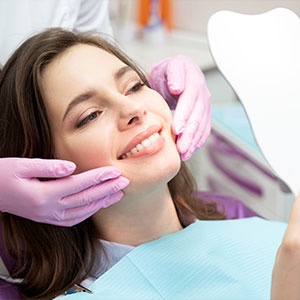 Woman sitting in dental chair with dental hygienist performing cleaning procedure.